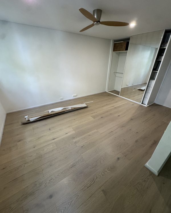 Wide-board engineered oak flooring laid through a light-filled bedroom