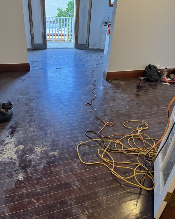Heavily worn dark floorboards before sanding begins