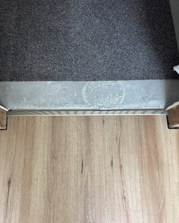 A trim strip forming a clean junction between carpet and timber flooring