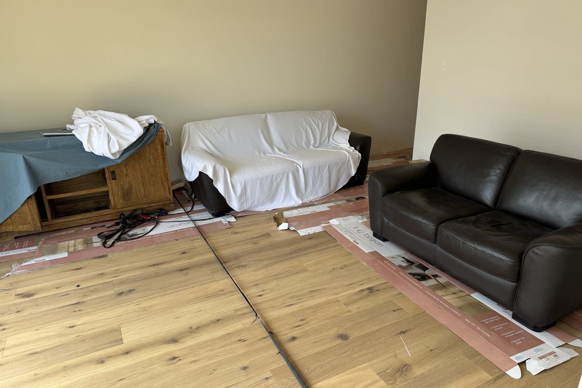 Furniture sheeted while engineered oak is laid around it