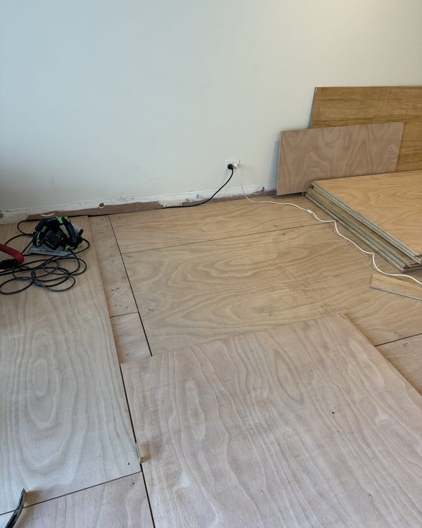 Plywood subfloor sheets being cut and laid before a timber floor